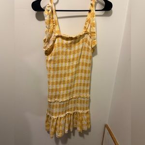 Yellow plaid drop-waist dress with smocking throughout. Tie bows on shoulders.